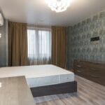 Minimalistyczna sypialnia z łóżkiem, szafą i nowoczesnym żyrandolem