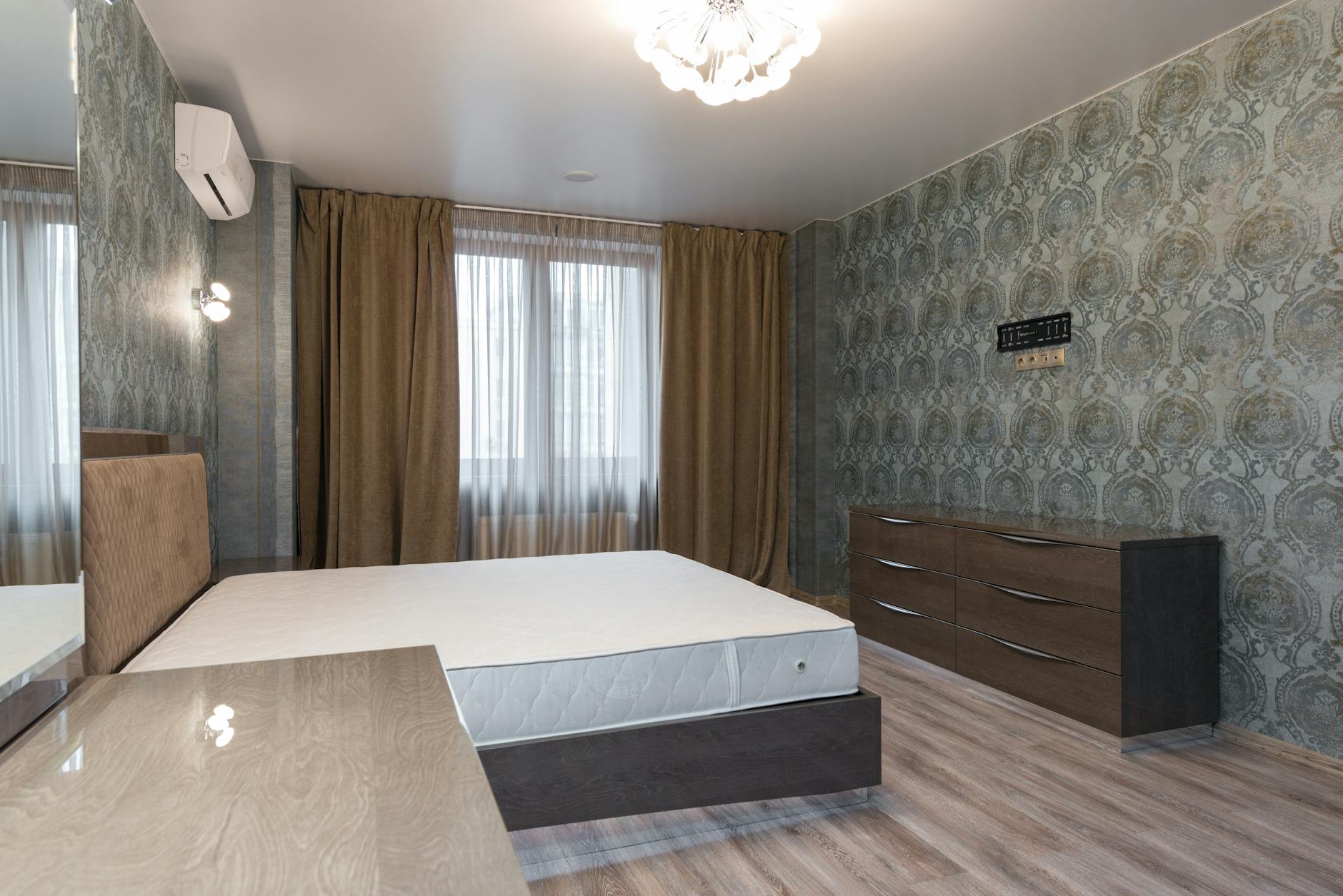 Minimalistyczna sypialnia z łóżkiem, szafą i nowoczesnym żyrandolem