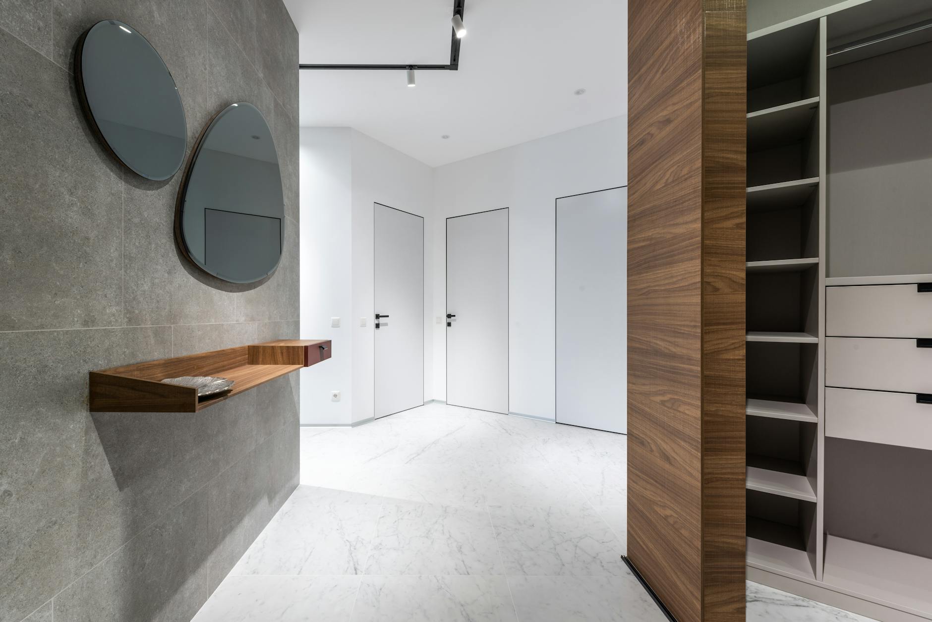 Przedpokój z dużą szafą wnękową, lustrami i drewnianą półką