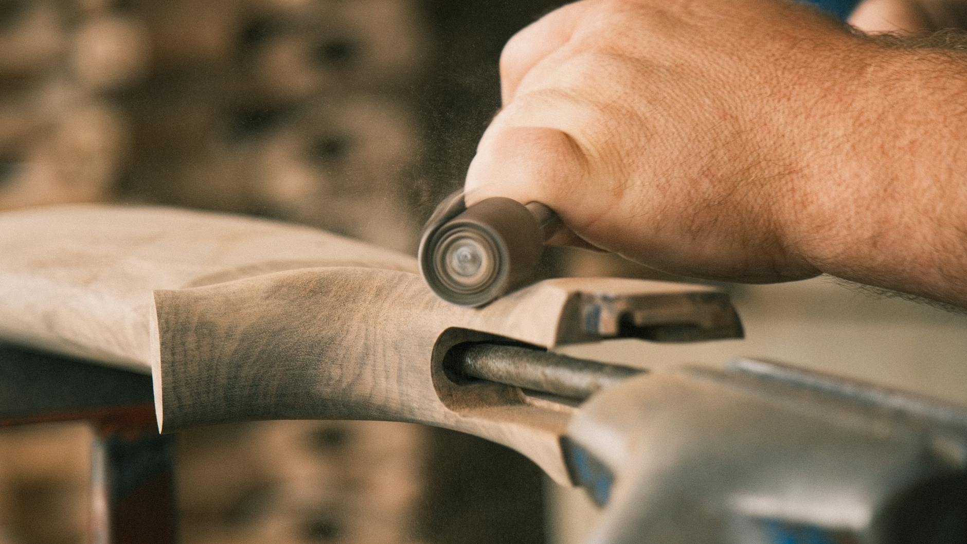 Stolarz obrabia drewniany mebel szlifierką w warsztacie