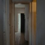 Wąski, słabo oświetlony korytarz w mieszkaniu z drewnianymi drzwiami