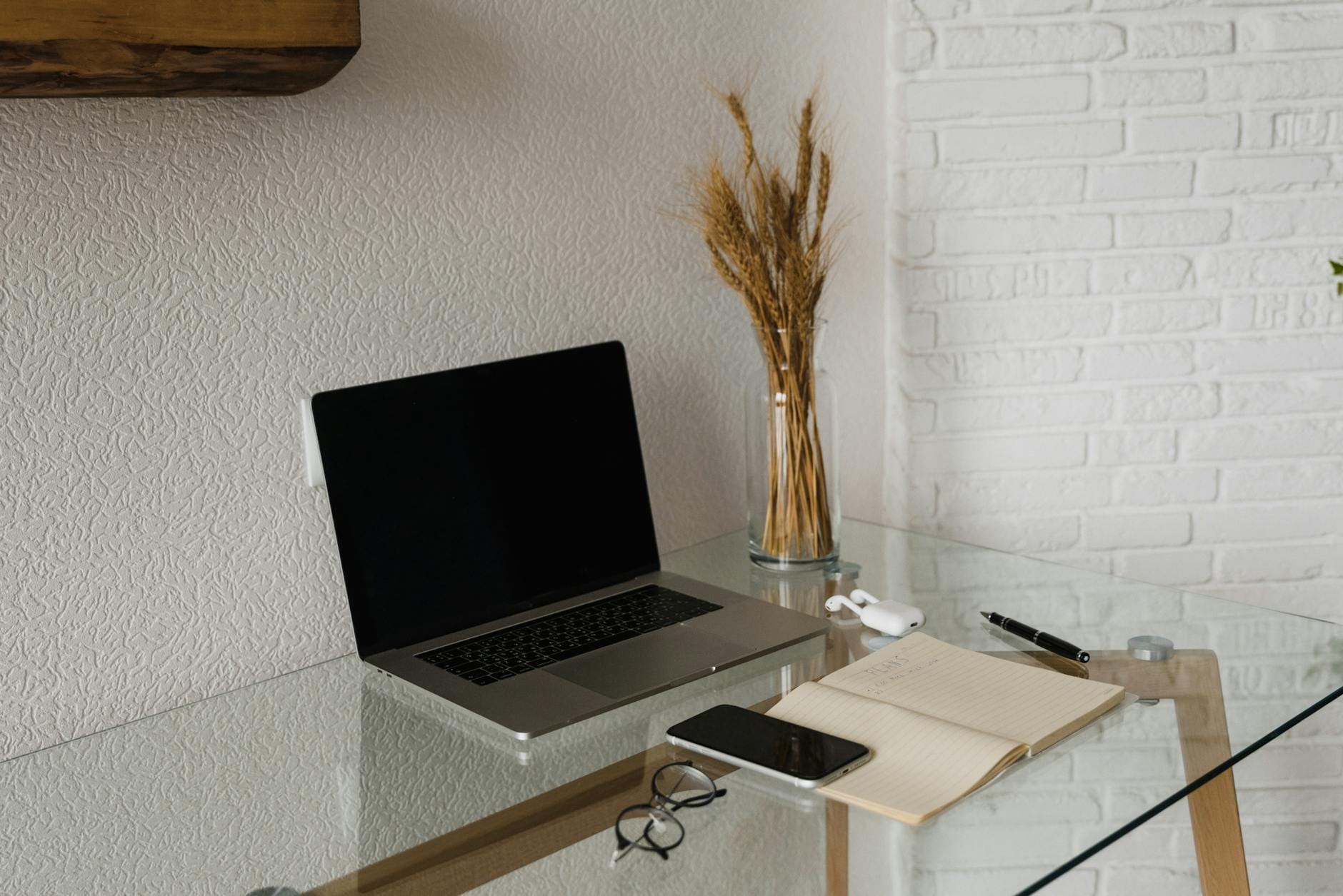 Szklane biurko z laptopem, smartfonem i notesem w domowym biurze