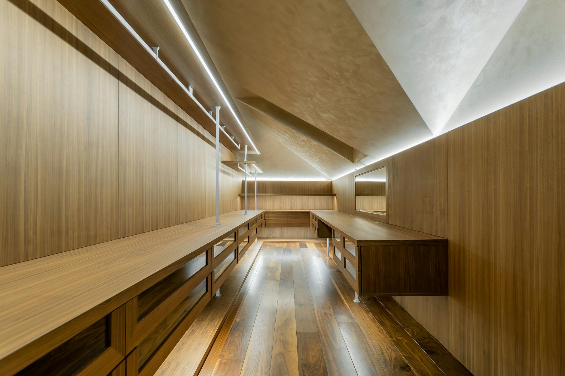 Nowoczesna, przestronna garderoba z drewnianą zabudową i oświetleniem