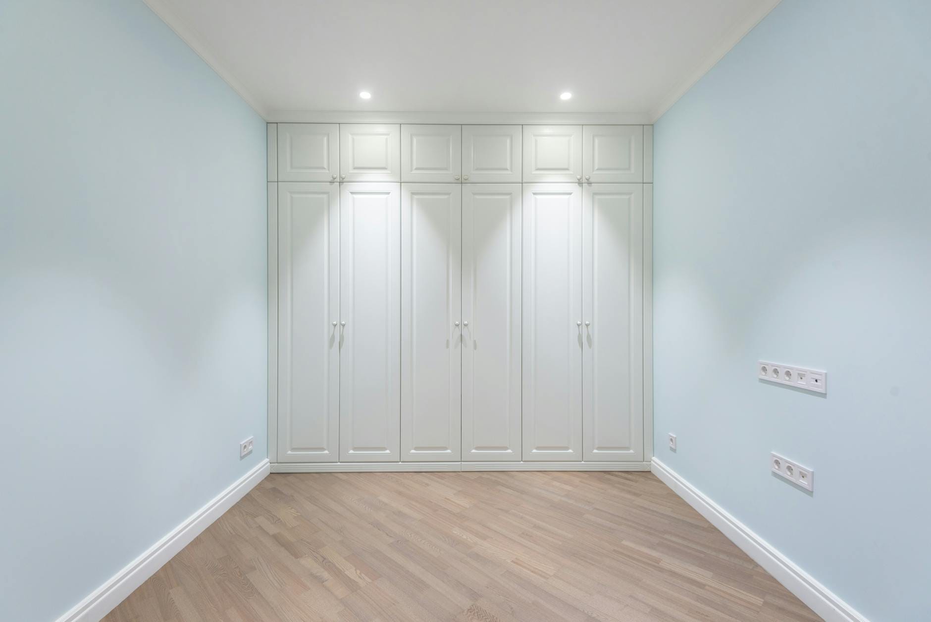 Pusta jasna sypialnia z szafą w zabudowie pod sam sufit