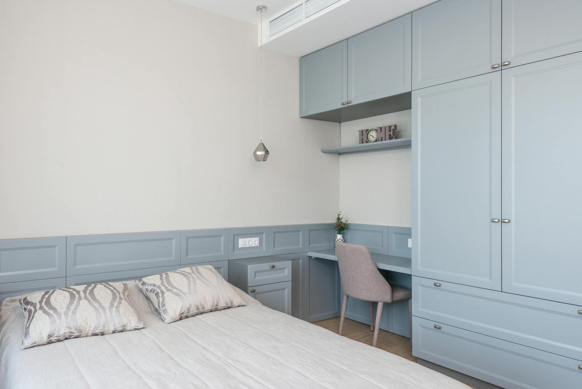 Sypialnia z zabudową łóżka, niebieskimi frontami i małym biurkiem