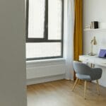 Jasne minimalistyczne domowe biuro z biurkiem przy oknie w żółtych zasłonach