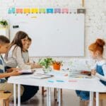 Nauczyciel rozmawia z uczniami w kolorowej klasie edukacji wczesnoszkolnej